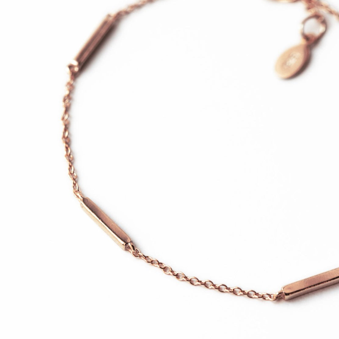 Rose gold vermeil bar station bracelet, close-up detail of the bars and thin chain on a white background