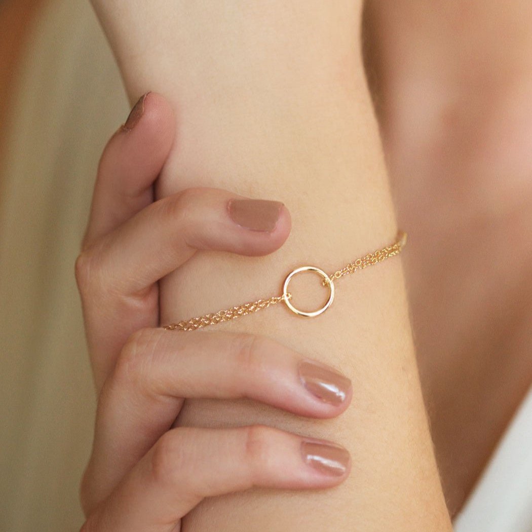 Gold vermeil eternity circle bracelet held in a hand, shown close-up on the wrist