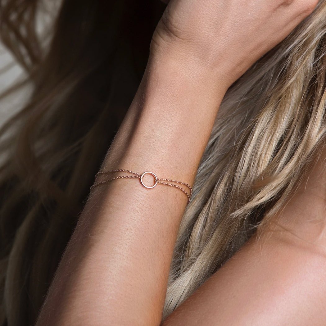 Rose gold vermeil eternity circle bracelet held in a hand, shown close-up on the wrist
