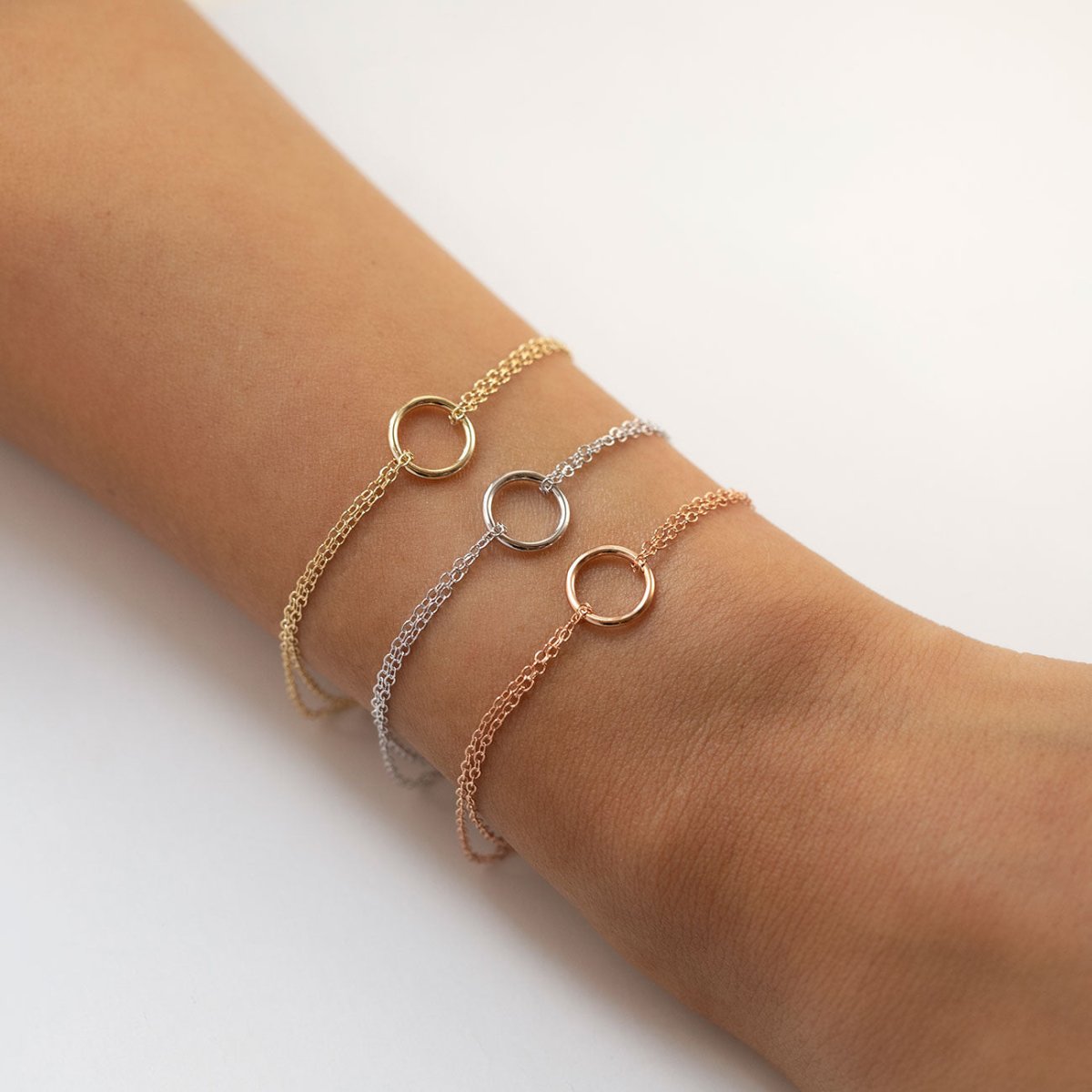 Sterling silver eternity circle bracelet shown stacked with gold and rose gold ones on a wrist