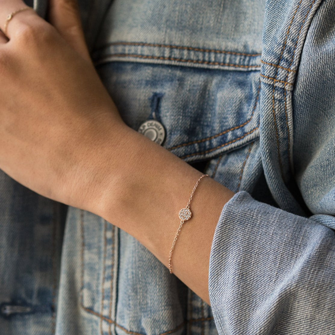 Rose gold vermeil pavé disc chain bracelet with white zirconia, shown on a model's wrist with denim