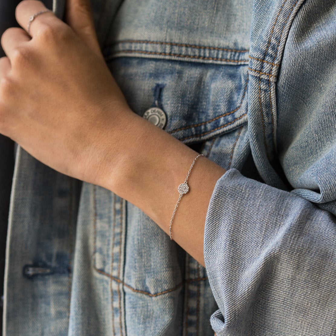 Sterling silver pavé disc chain bracelet with white zirconia, shown on a model's wrist with denim