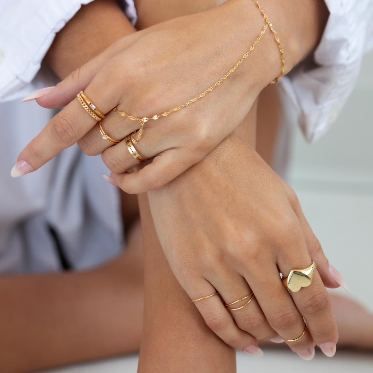 Gold-filled engraved band and signet rings stacked with chains, shown on a model's hands
