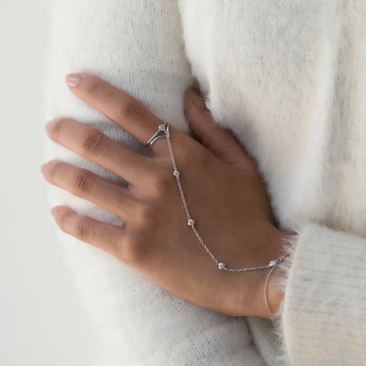 Sterling silver hand chain with clear stones and a ring, shown on a model's hand