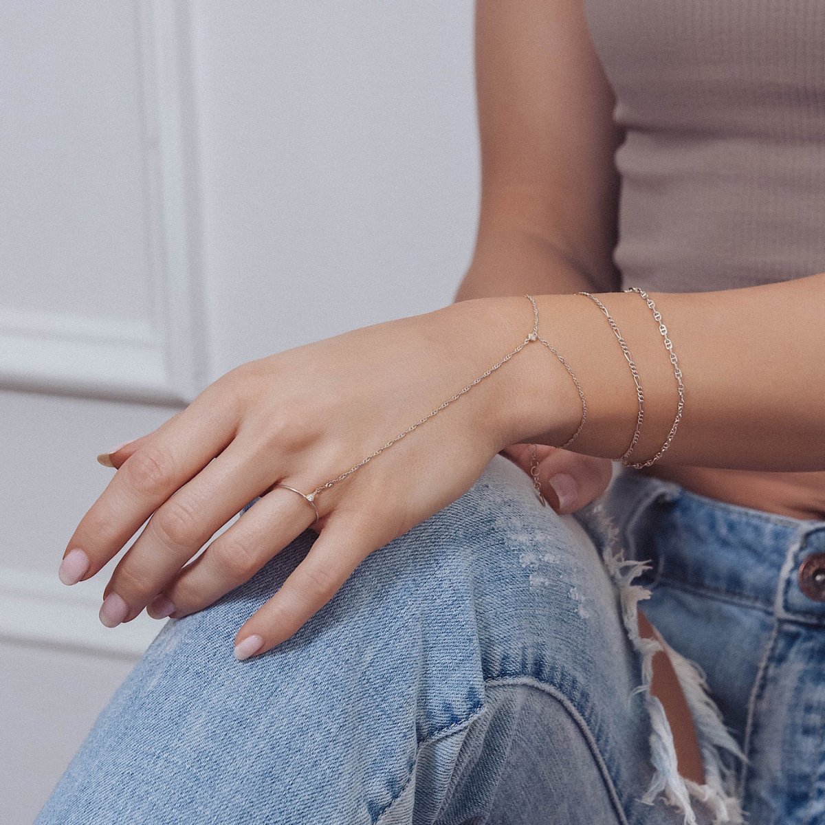 Sterling silver Figaro chain bracelet stacked with delicate chains, shown on a model's wrist