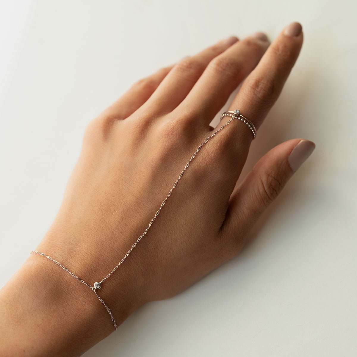 Sterling silver handchain with a clear stone, shown on the back of a model's hand on a white background