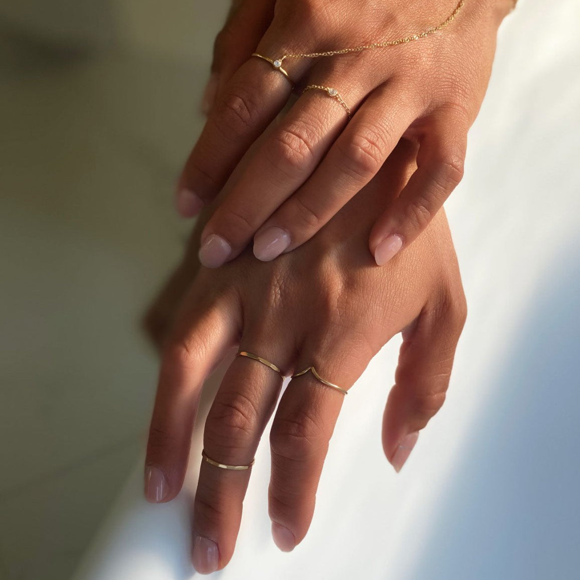 Gold-filled hammered thin stacking rings shown on a model's fingers in soft light
