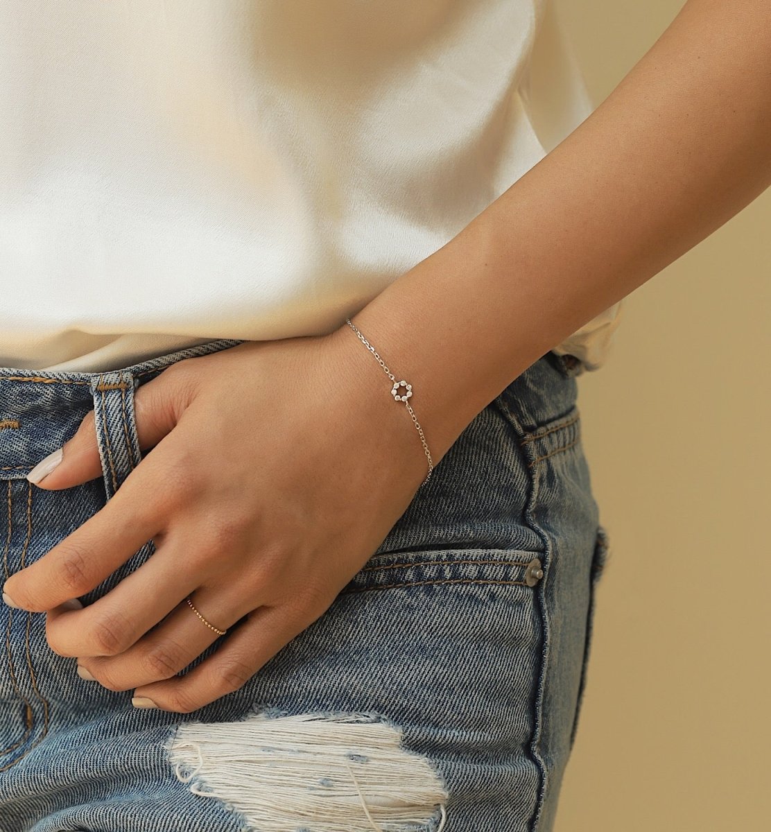 Sterling silver thin chain bracelet with a zirconia open circle, shown on a model's wrist