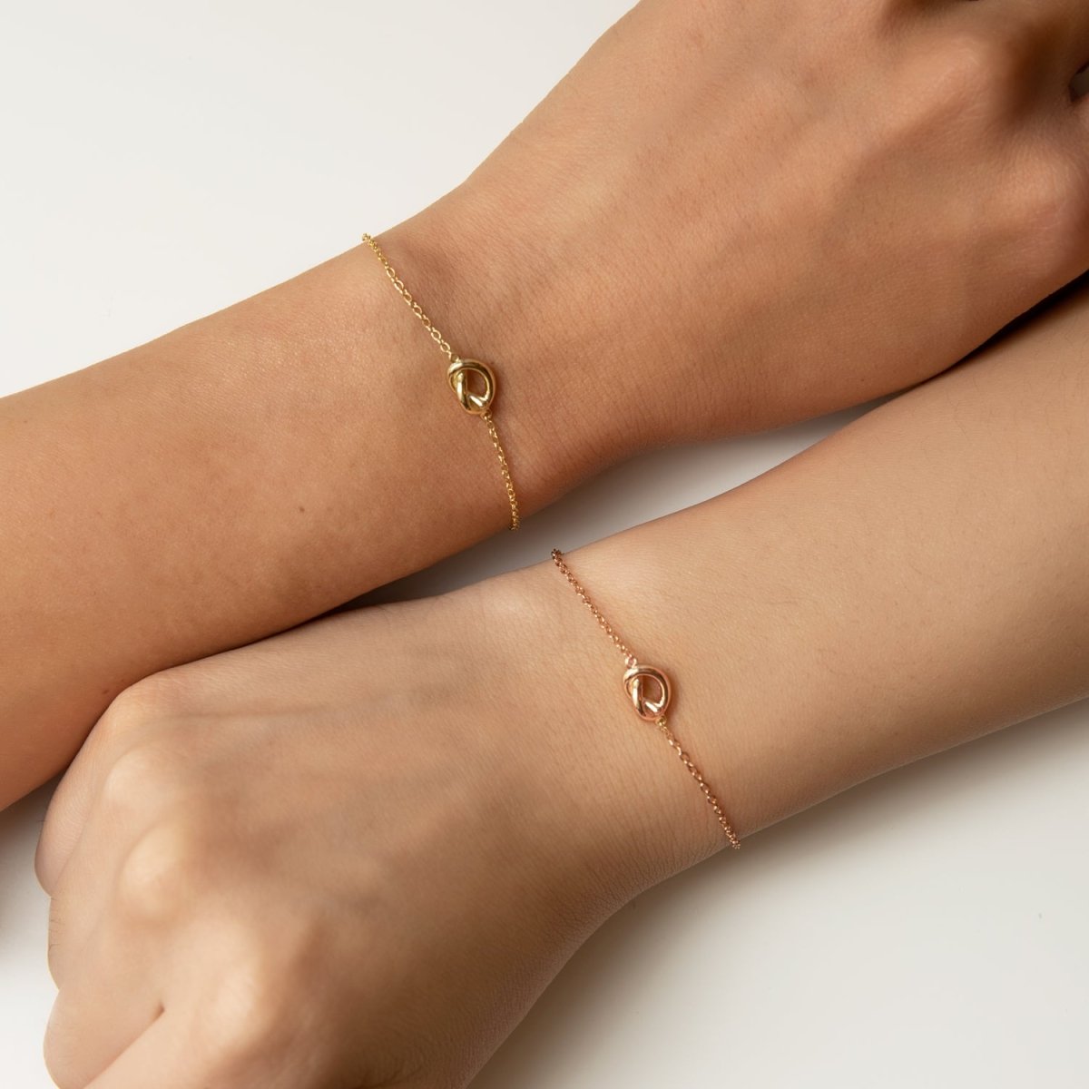 Gold and rose gold vermeil love knot bracelets shown side by side on two models' wrists