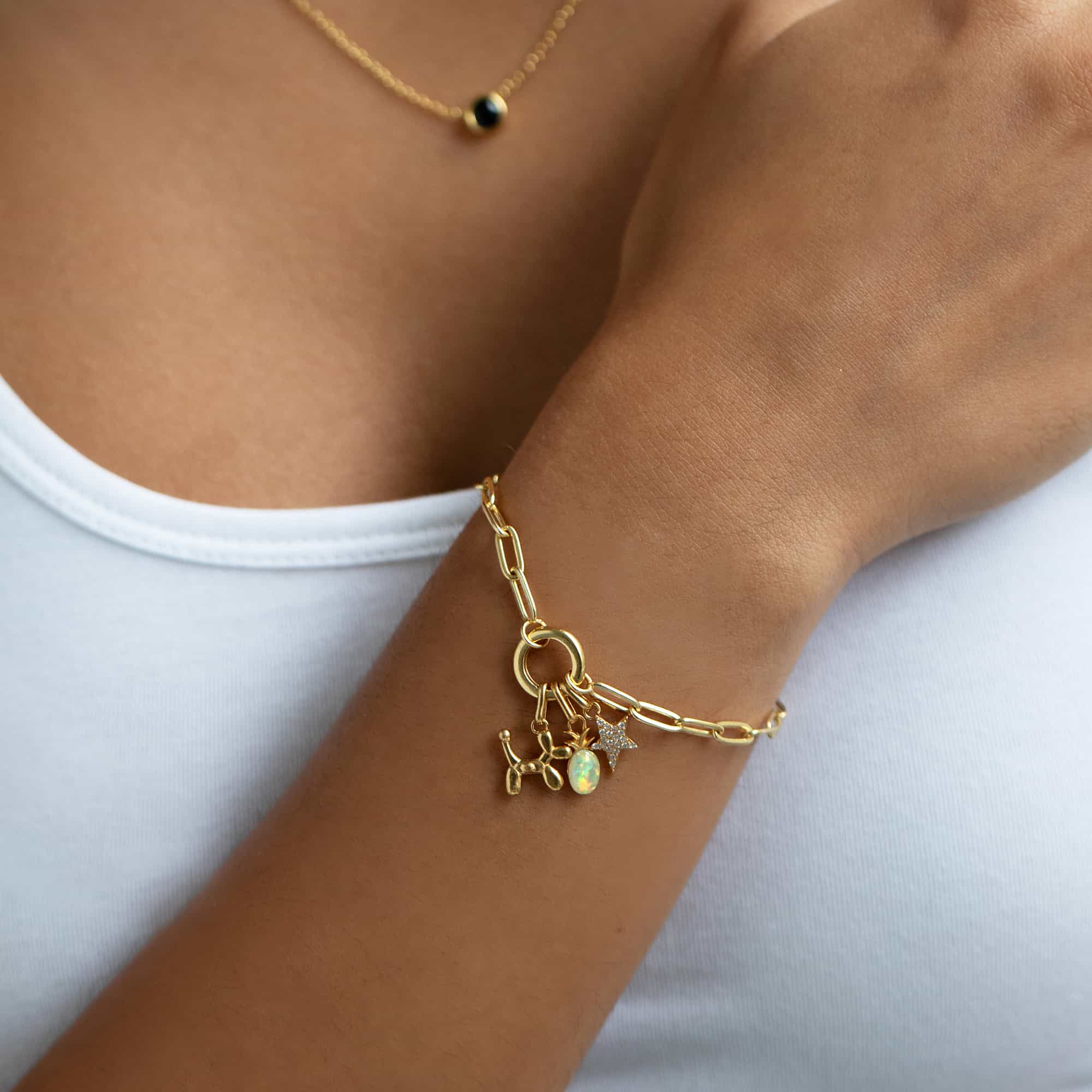 Gold vermeil balloon dog charm on a paperclip chain bracelet, shown close on a model's wrist