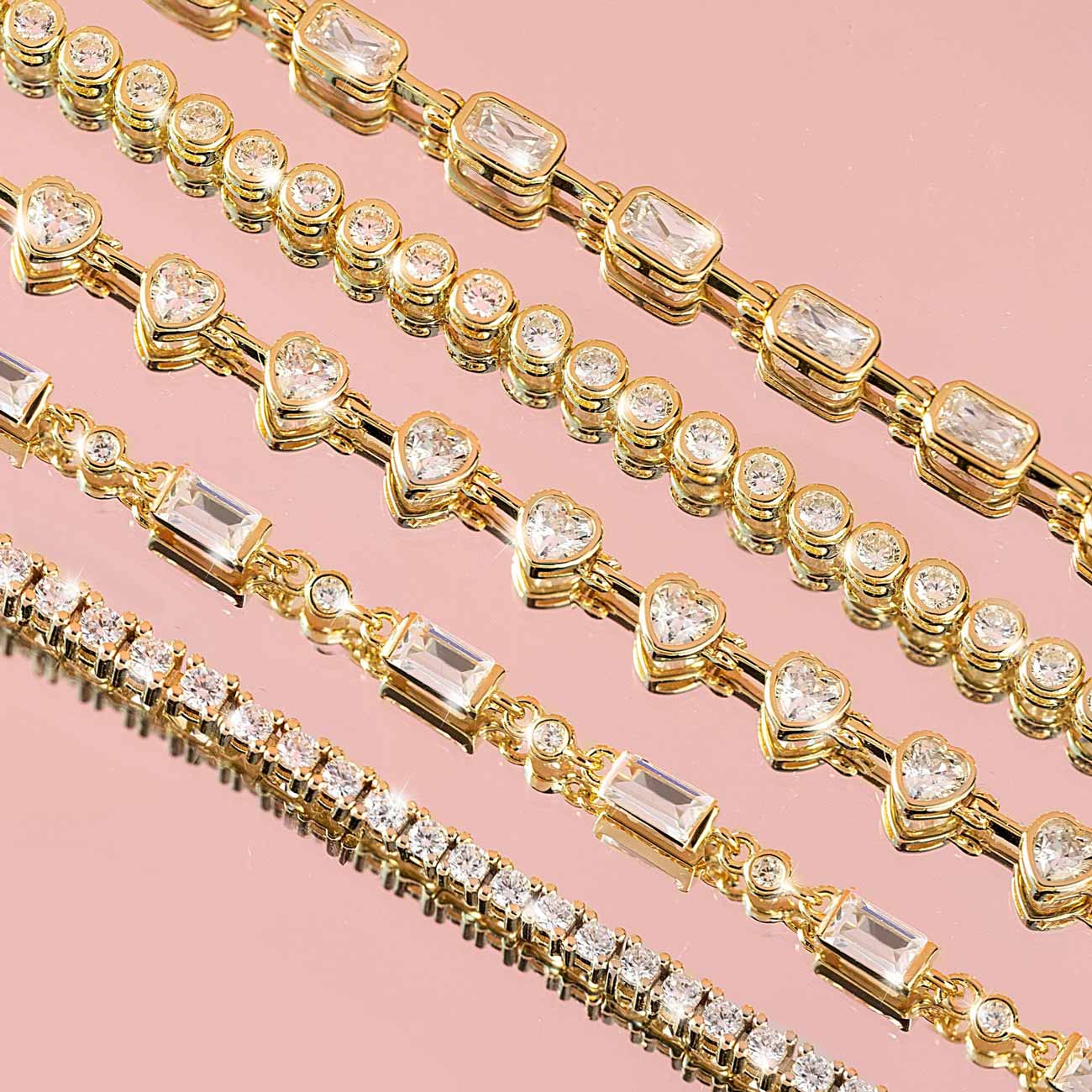Gold tennis bracelets with mixed-cut clear stones, close-up detail on pink