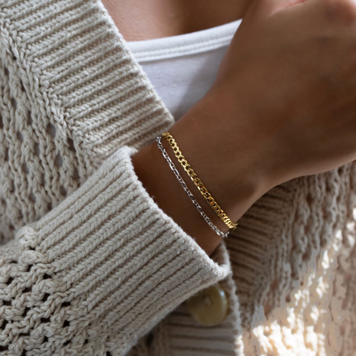 Gold vermeil Cuban curb chain bracelet layered with a silver chain, shown on a model's wrist