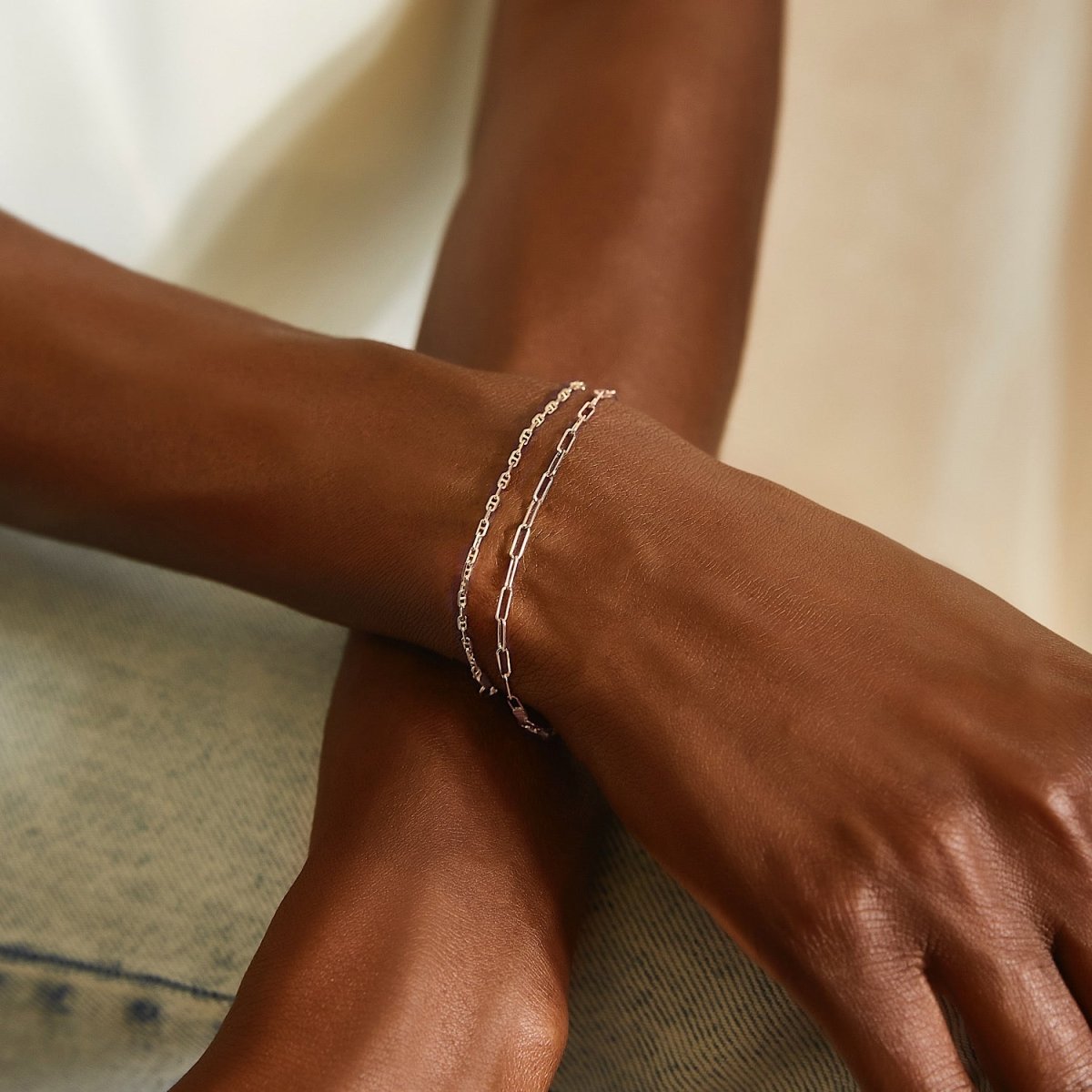 14K white gold paperclip chain bracelet layered with a finer chain on a model's wrist