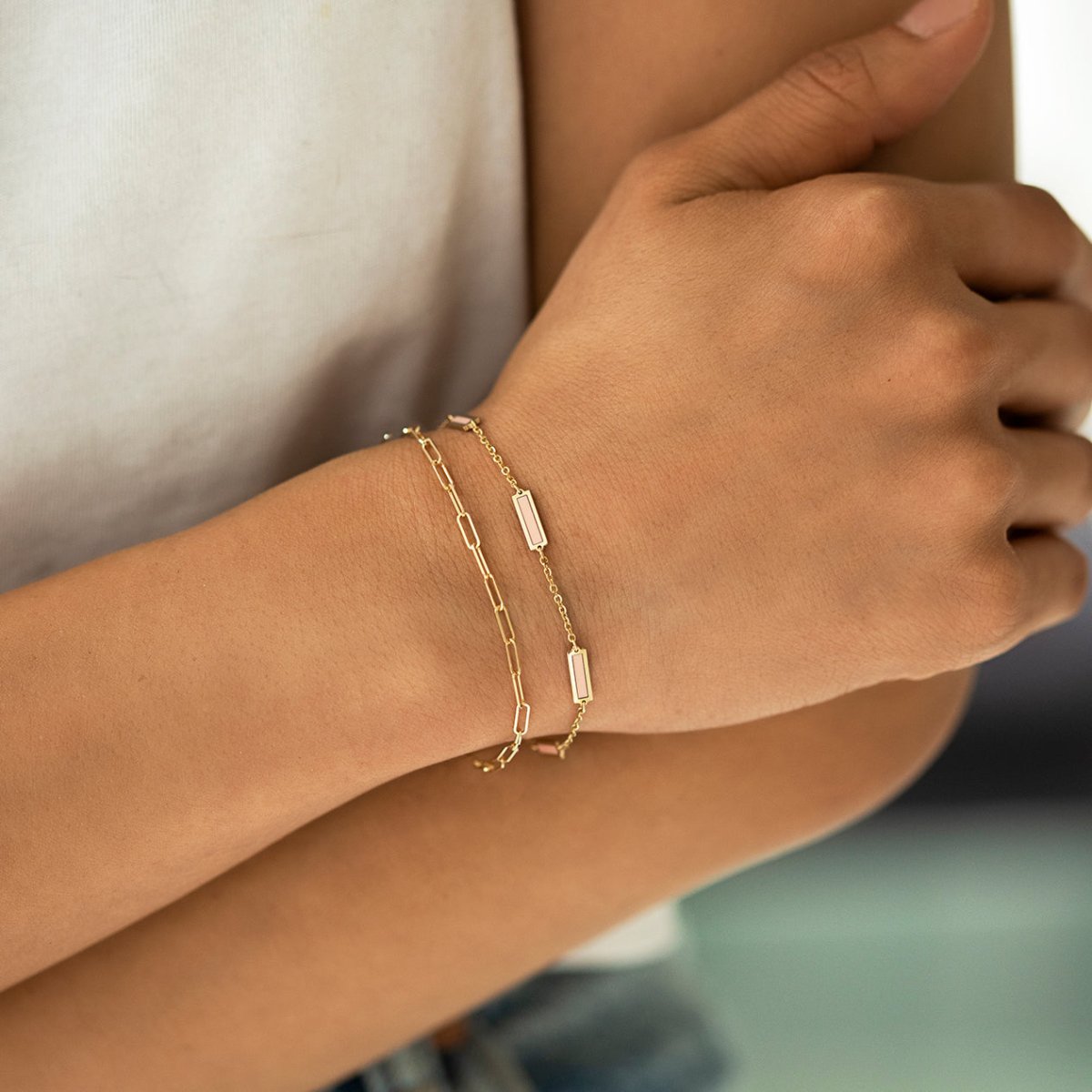 14K gold rose quartz bar bracelet with pink stations, layered and shown on a model's wrist