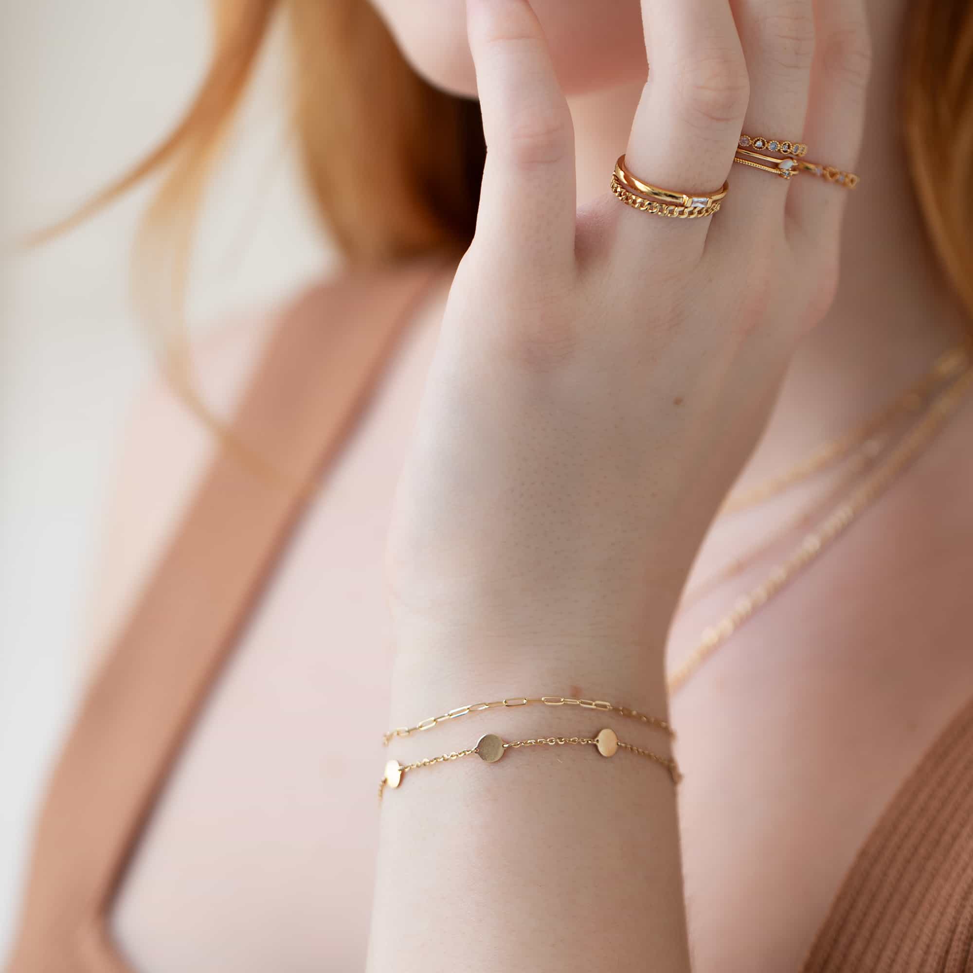 Gold disc-station and chain bracelets layered on a model's wrist