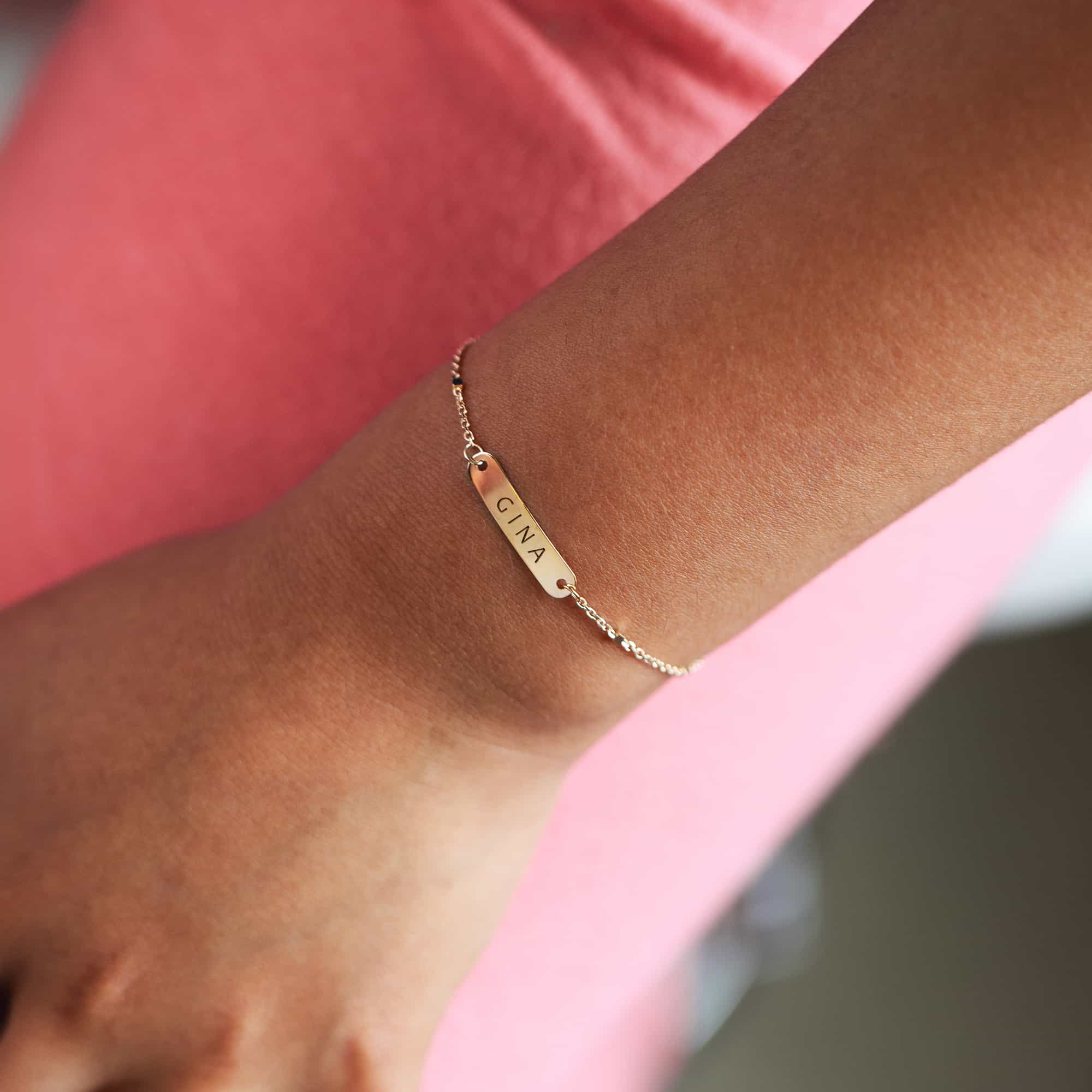 14K gold ID bracelet engraved name on a beaded chain, shown on a model's wrist