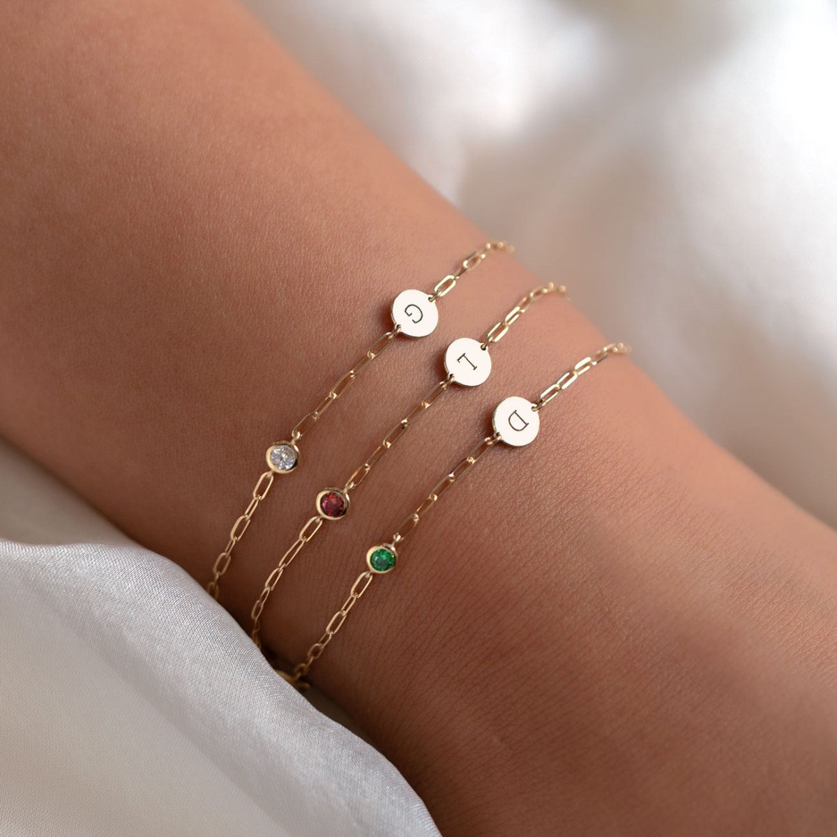 14K gold initial disc bracelet with a moissanite accent and lobster clasp, on a white background