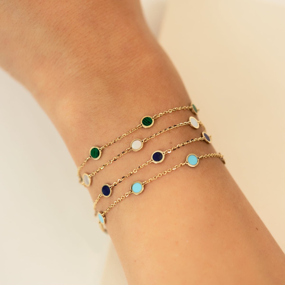 14K gold bezel-set station bracelets with green, blue and turquoise discs, layered on a wrist