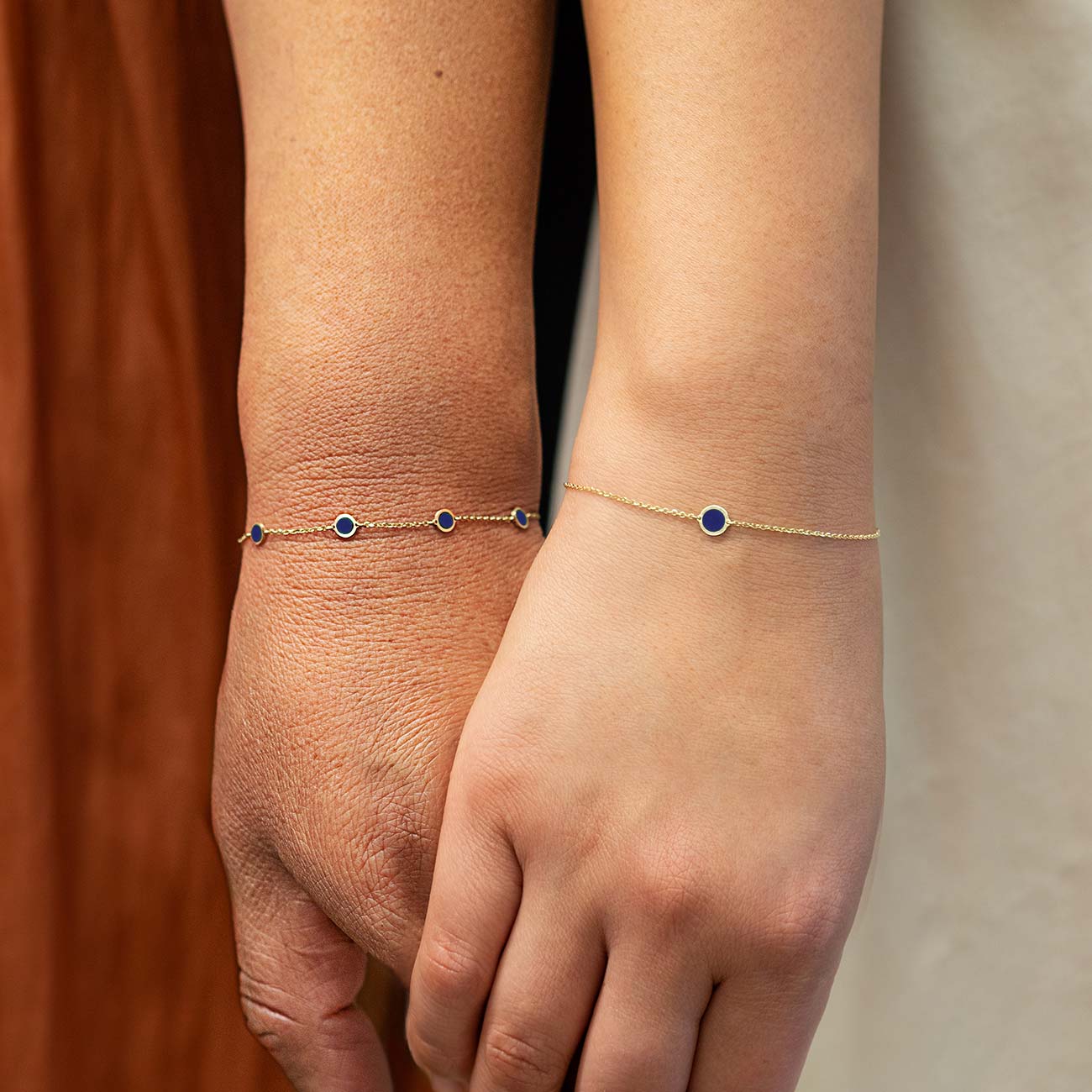 14K gold lapis lazuli disc bracelets shown layered on two models' wrists