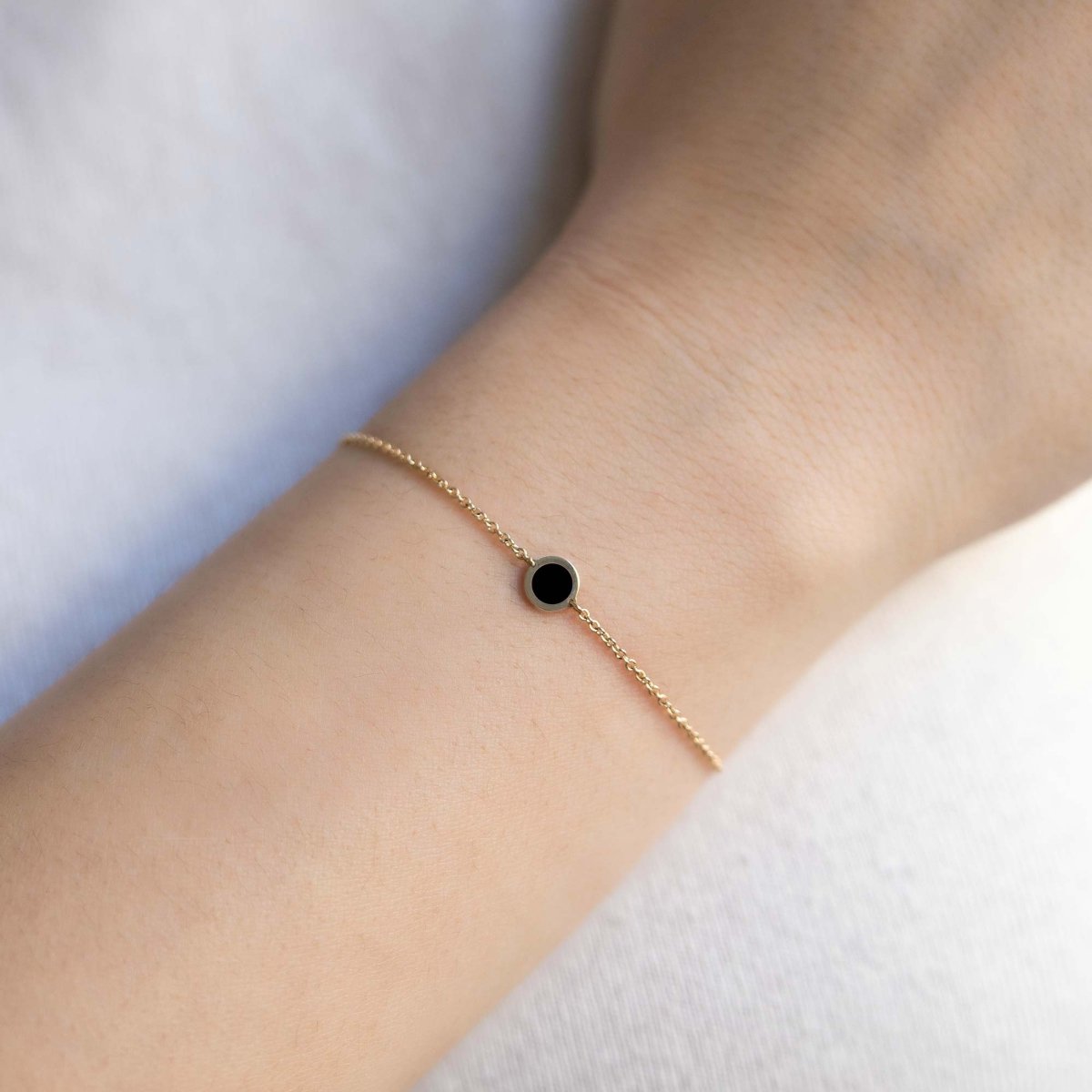 14K gold chain bracelet with a single round black onyx stone, shown on a model's wrist
