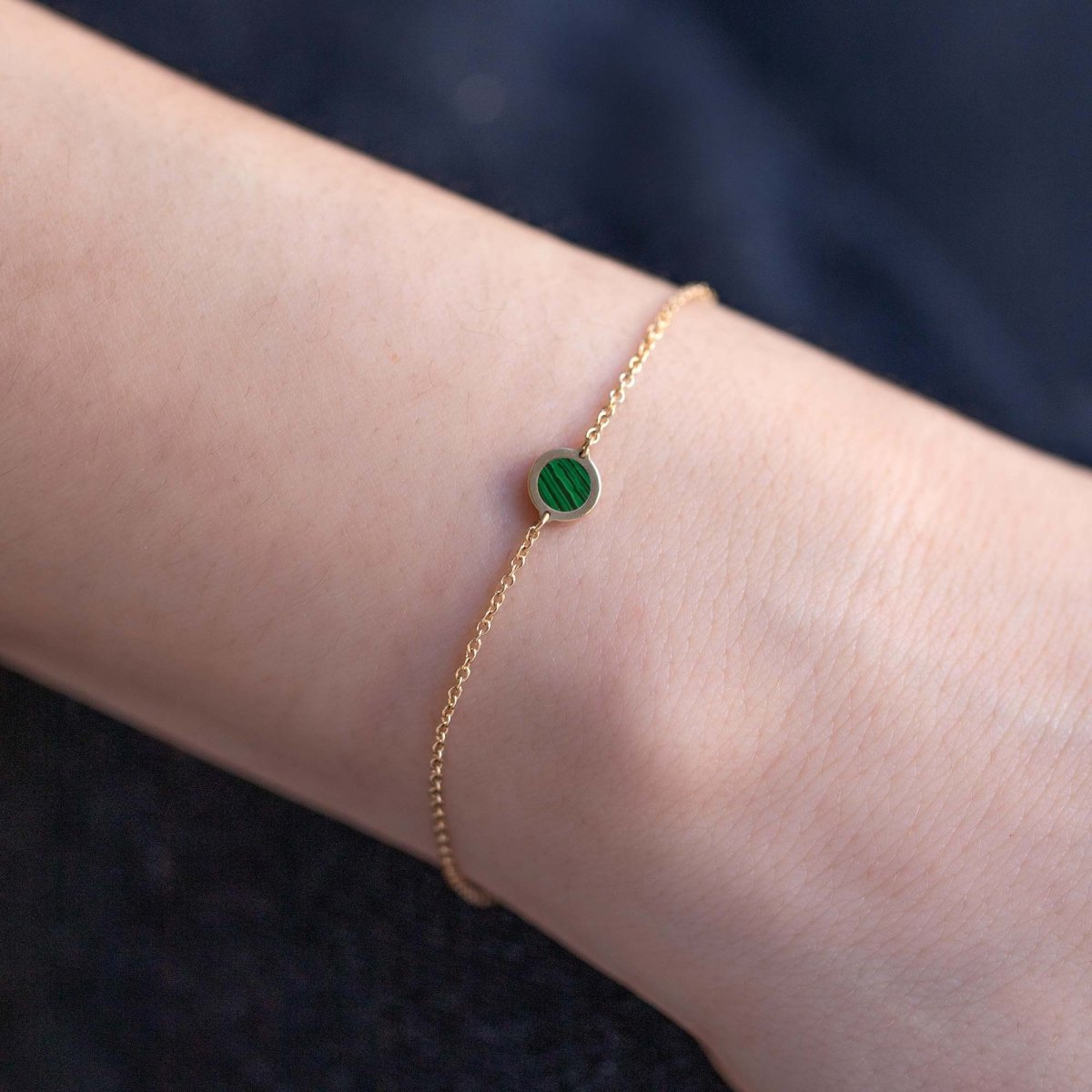 14K gold chain bracelet with a single round green malachite stone, shown on a model's wrist