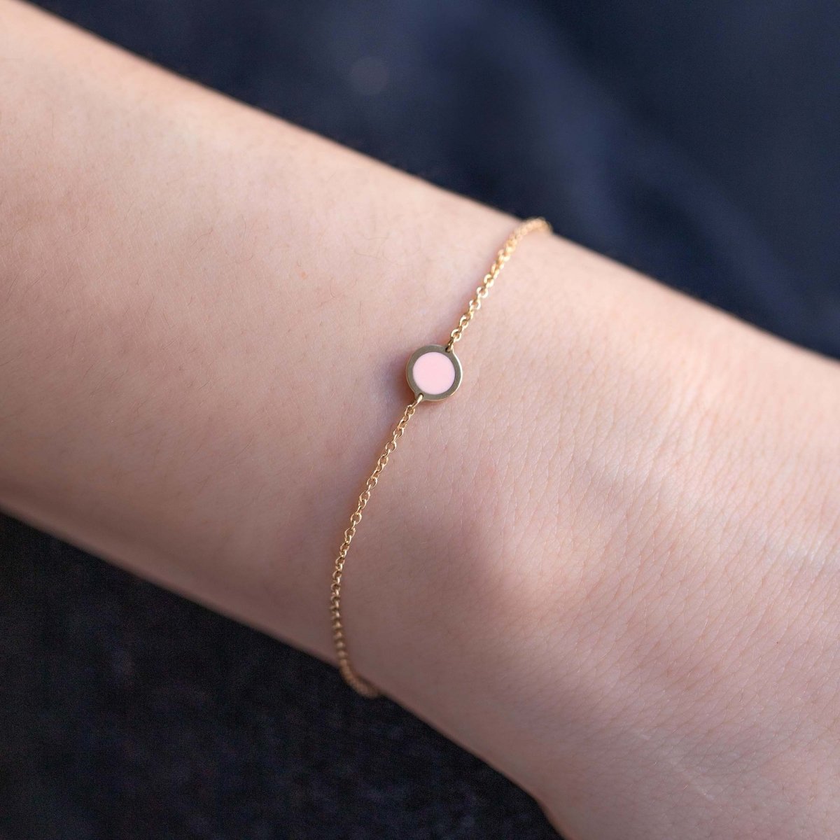 14K gold chain bracelet with a small round pink rose quartz stone, close-up on a model's wrist