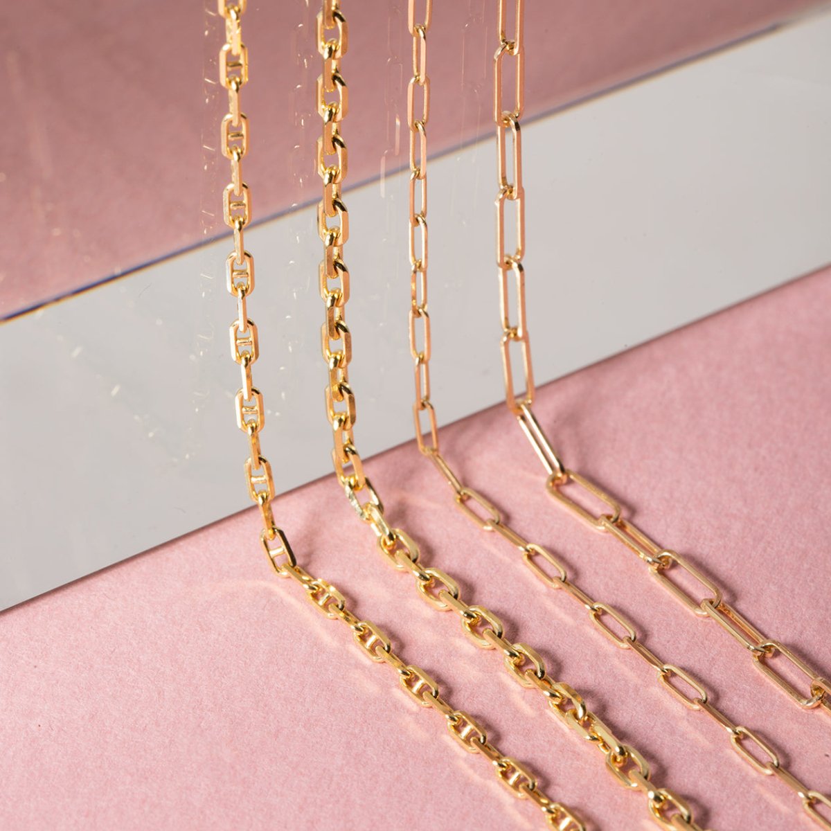 14K gold paperclip chain bracelet layered with a delicate heart-link chain, shown on a model's wrist