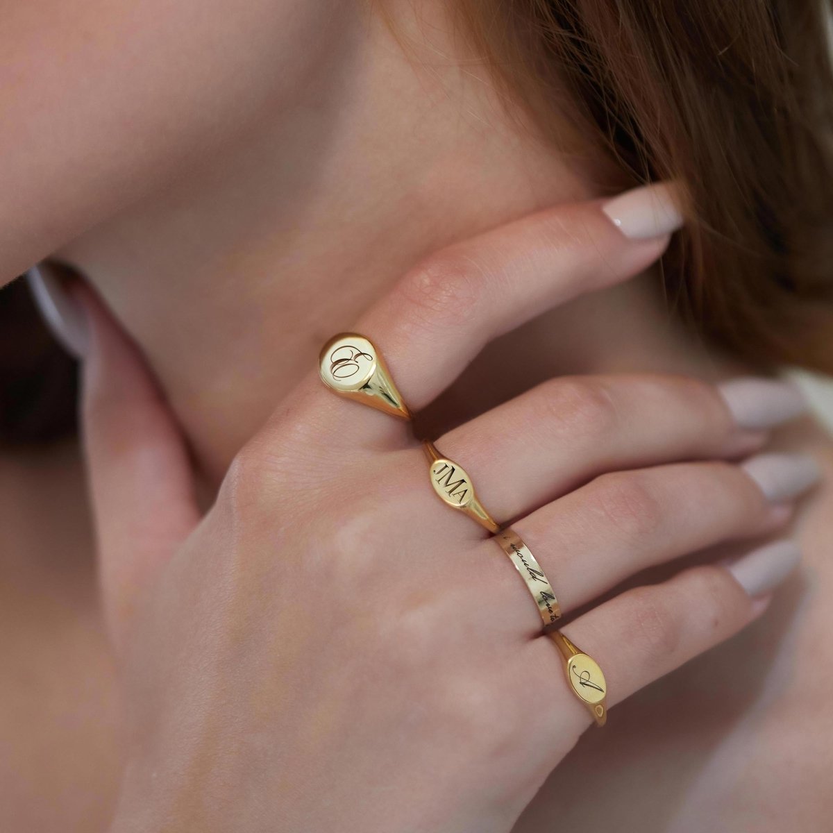 Gold vermeil oval signet ring engraved with an initial, stacked with bar rings on a model's hand