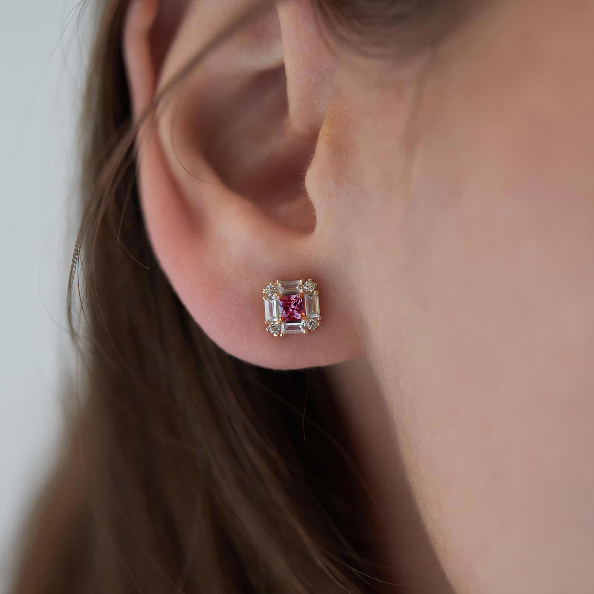 14K gold deco stud with a square ruby center and clear baguette and round stones, shown on a model's ear
