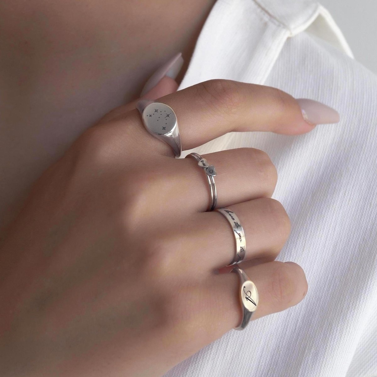 Sterling silver engraved band and signet rings with script and an initial, shown on a model's hand
