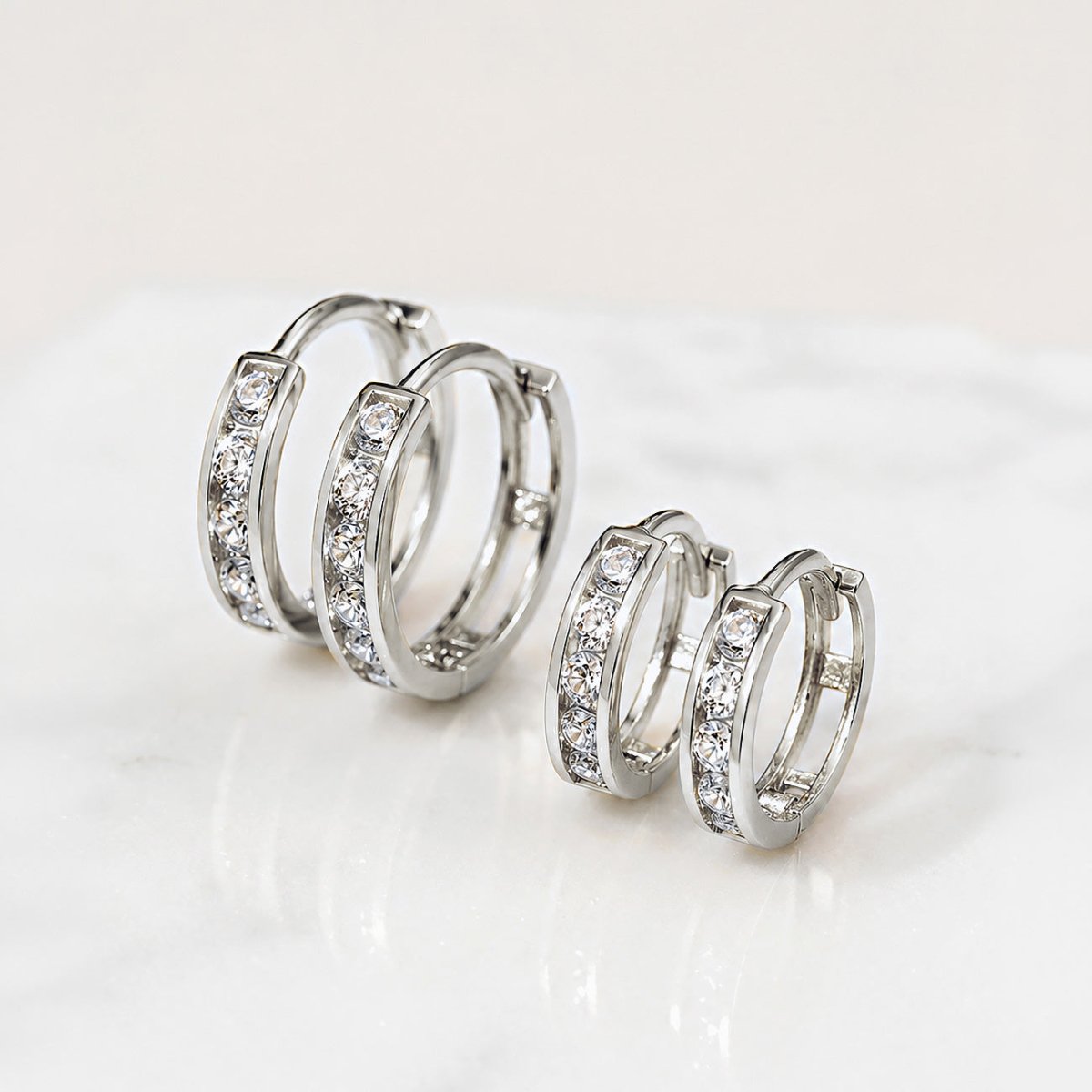 Pair of 14K white gold pavé huggie hoops with round crystals shown in a close-up.