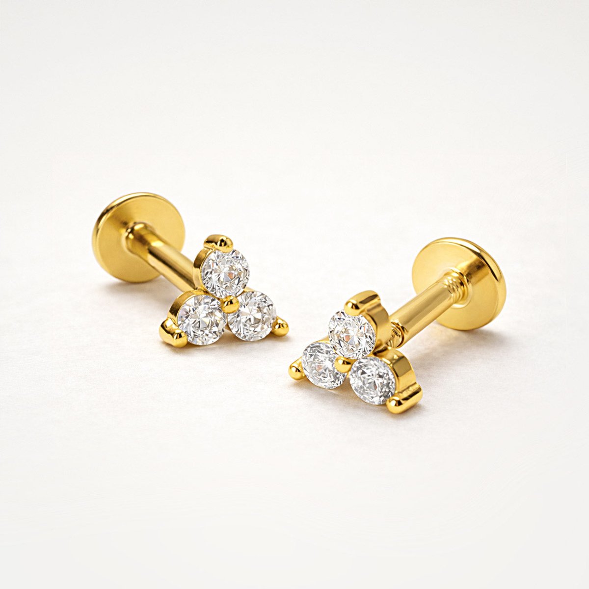 Pair of gold vermeil trio white zirconia flat back studs, close-up detail on a cream background
