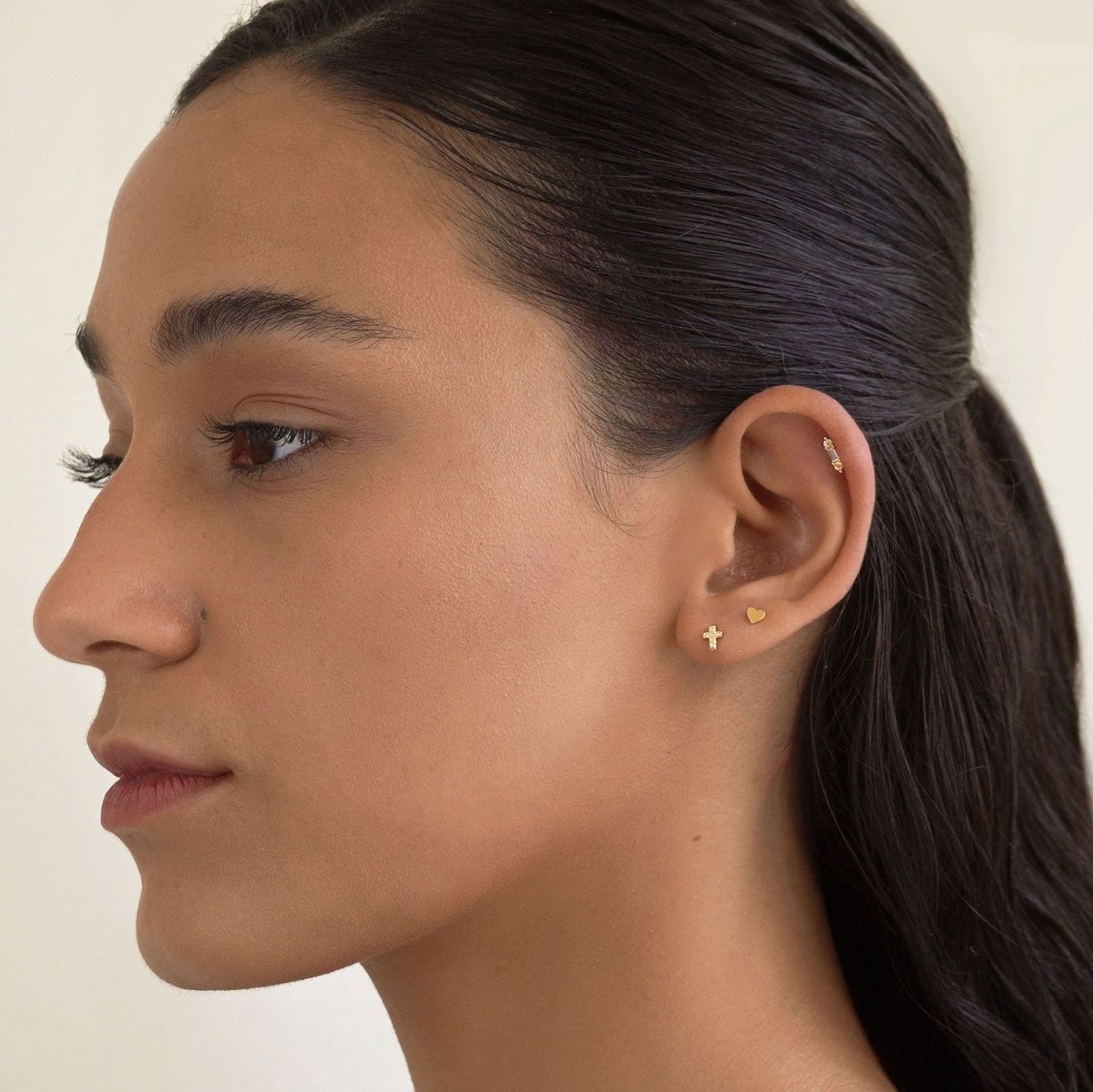 Gold vermeil pavé zirconia cross stud shown on a model's lobe in an ear stack