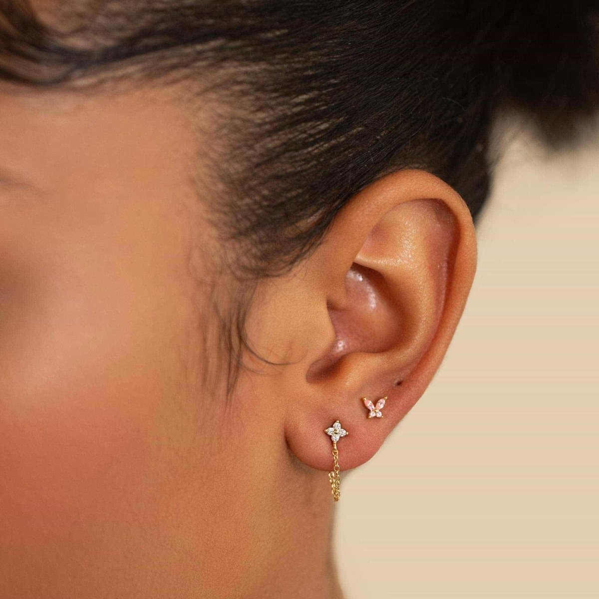Gold vermeil pink sapphire butterfly stud shown on a model's lobe with a clear flower chain stud