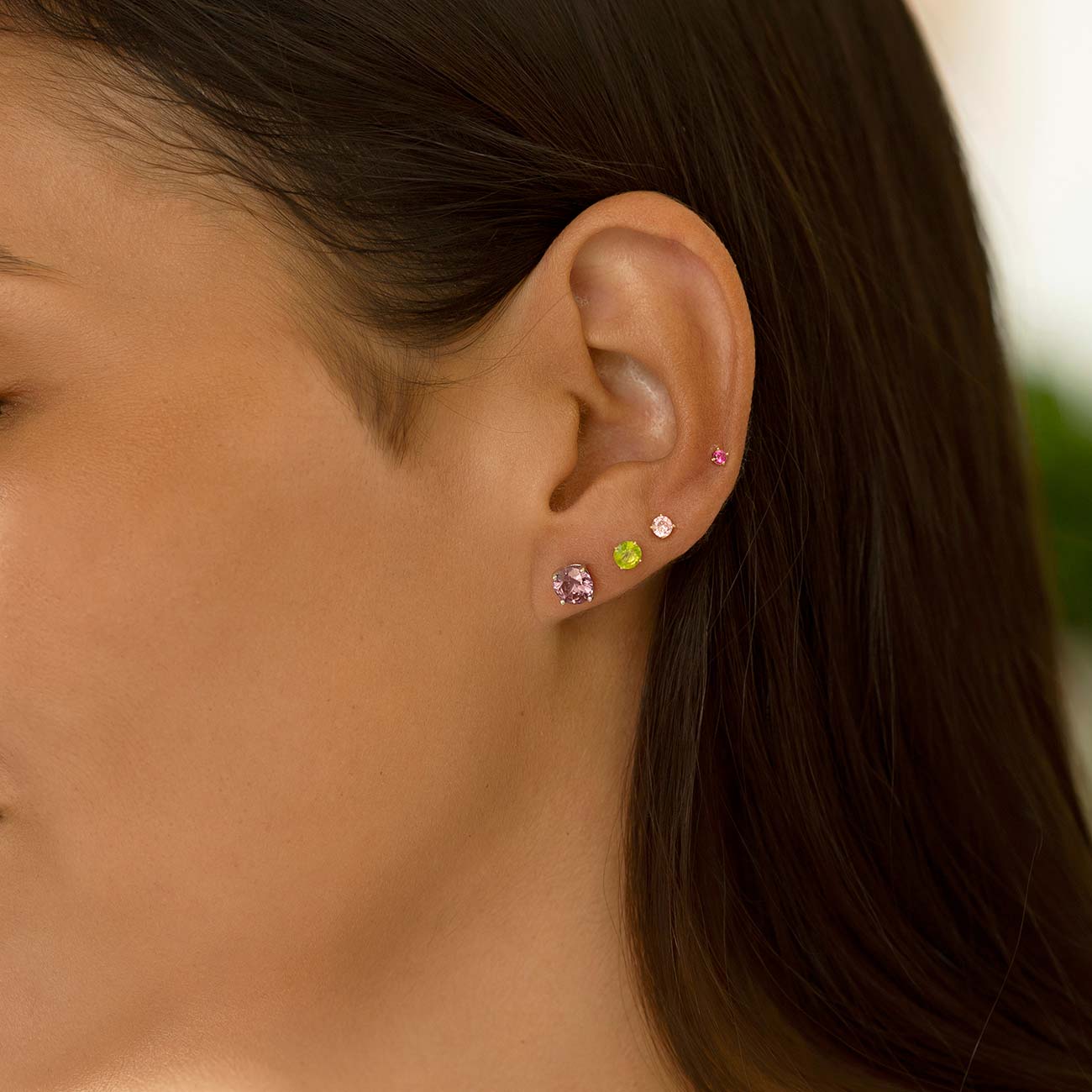 Sterling silver alexandrite stud in an ear stack of colored stone studs on a model's lobe and helix
