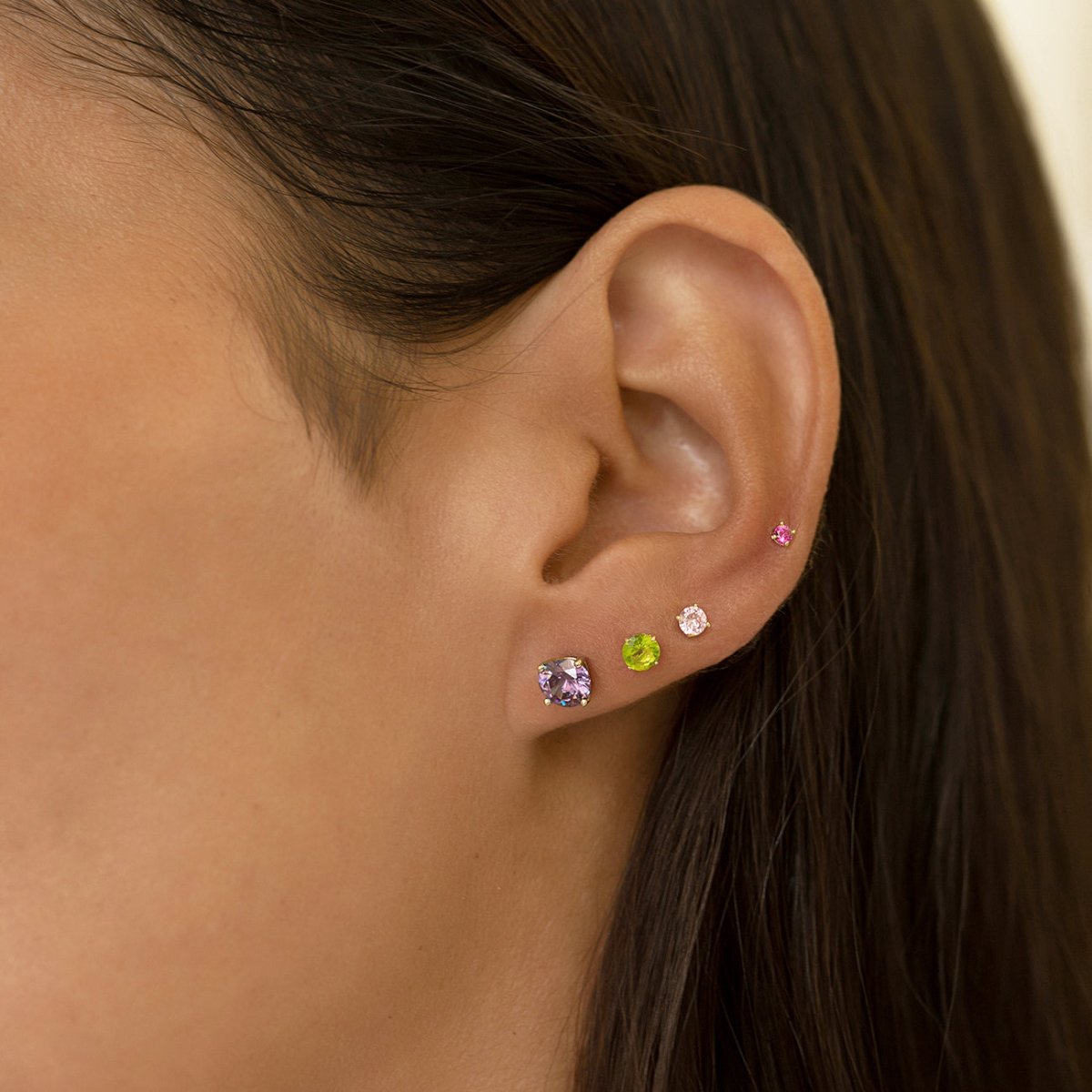 Sterling silver amethyst stud styled in an ear stack of colored stone studs on a model's lobe