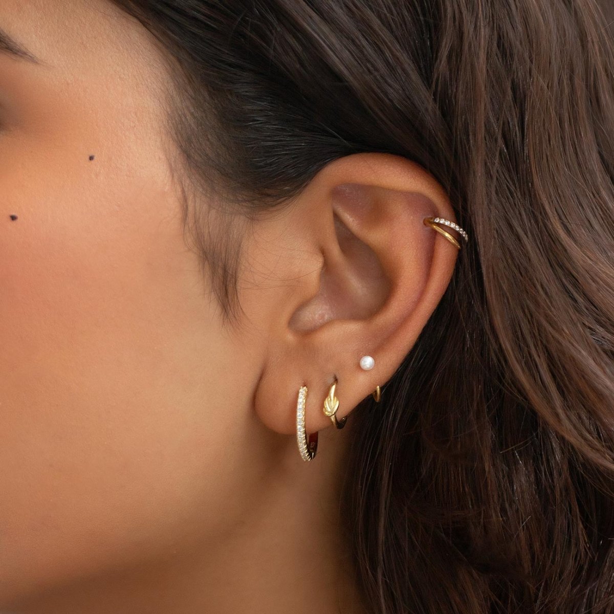 Gold vermeil pavé white zirconia small hoop styled with other earrings in a model's ear stack