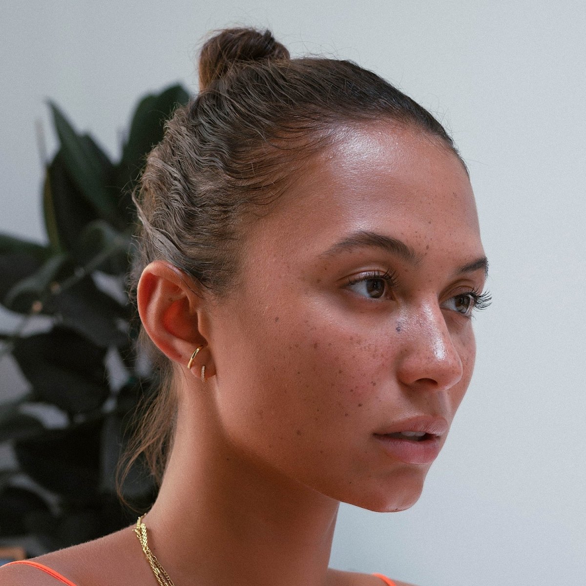 Gold vermeil small huggie hoops shown stacked on a model's lobe