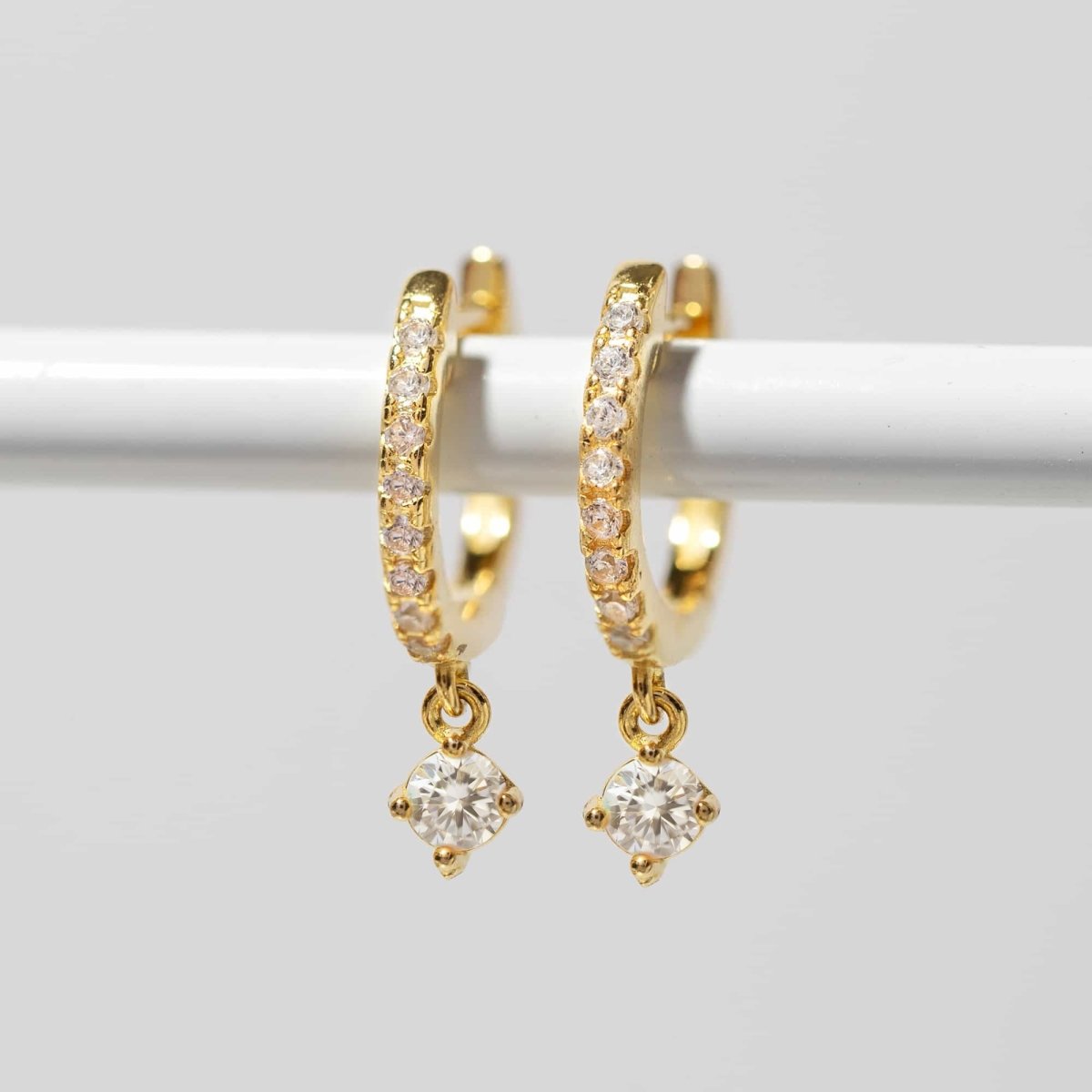 Gold vermeil pavé huggie hoops with a clear white zirconia drop, on a white background