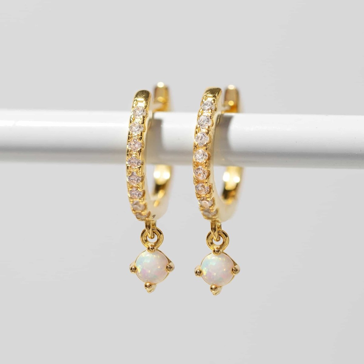 Gold vermeil pavé huggie hoops with a prong-set white opal drop, on a white background
