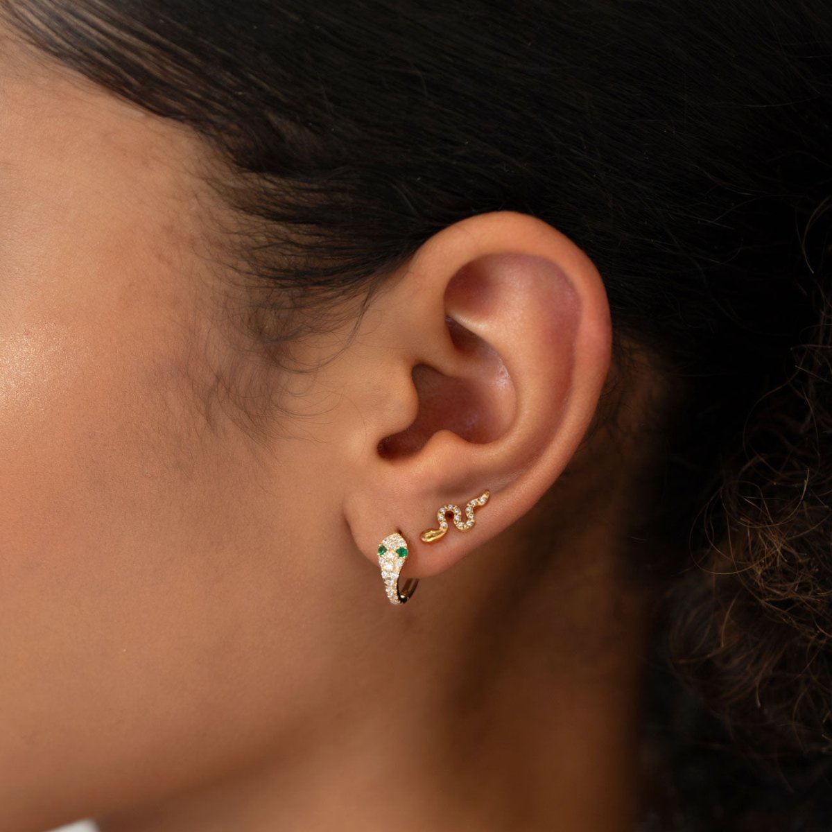 Gold vermeil pavé snake huggie hoop with clear stones, shown on a model's ear lobe