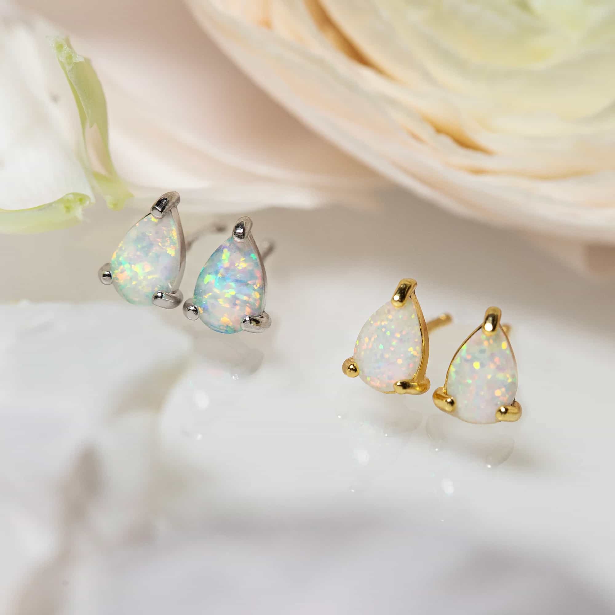 Gold vermeil and silver pear-shaped white opal studs styled together near a pale rose