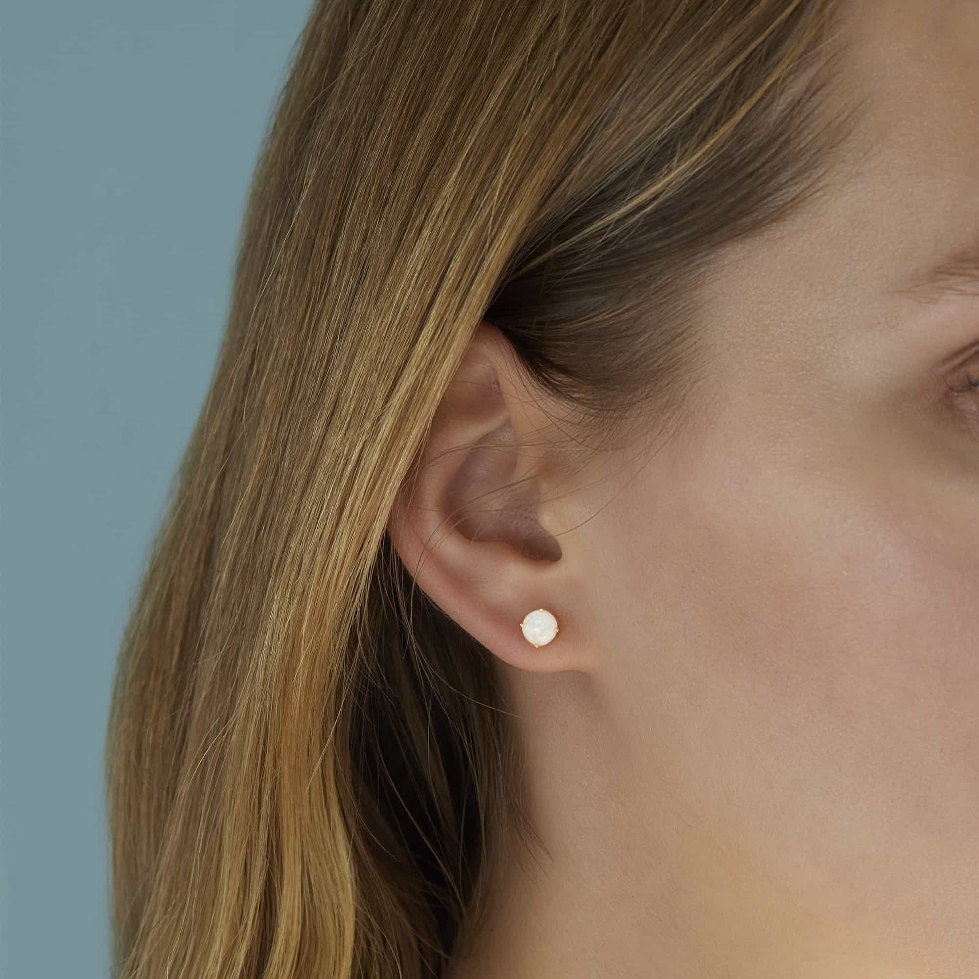 Sterling silver solitaire white opal stud earring shown on a model's lobe