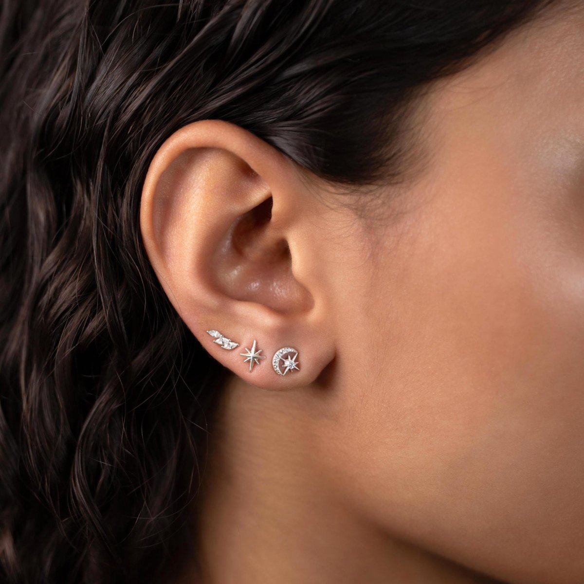 Sterling silver moon and star studs with clear zirconia styled in an ear stack on a model's lobe