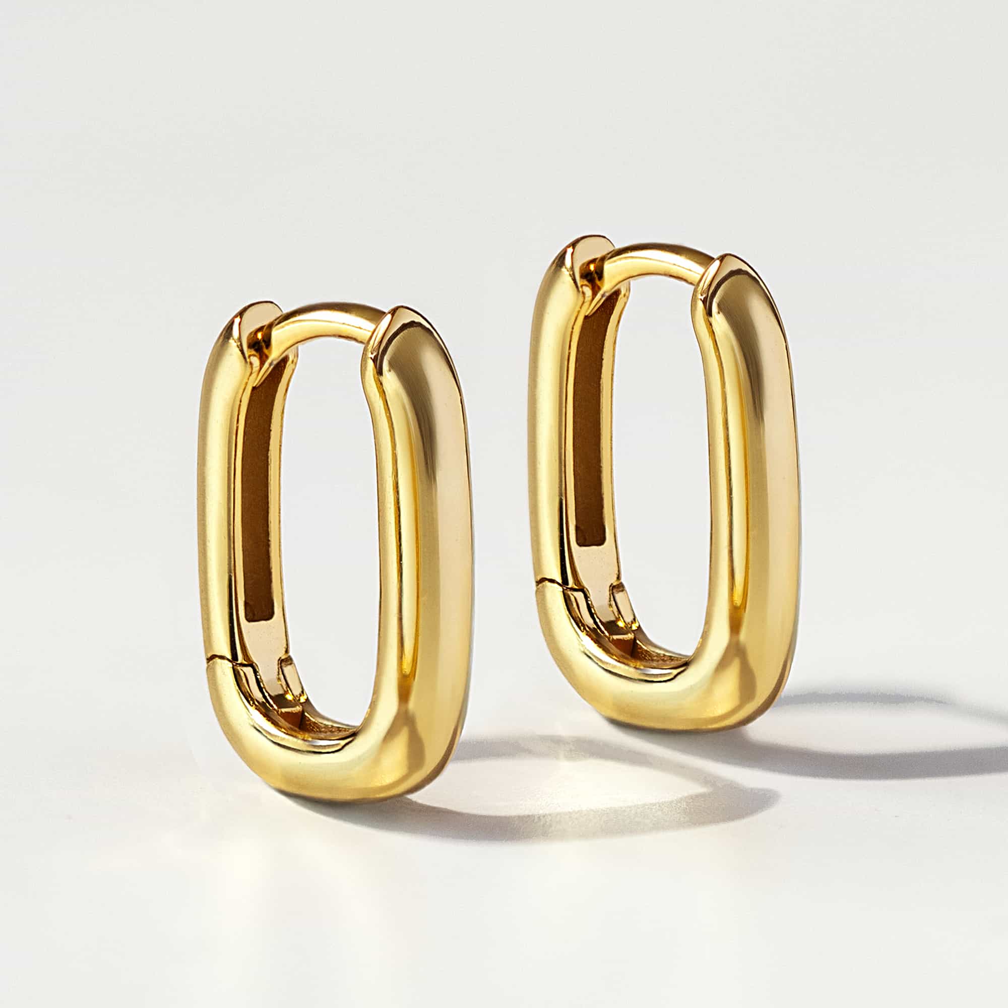 Pair of gold vermeil U-shaped huggie hoops with a chunky rounded profile, on a cream background