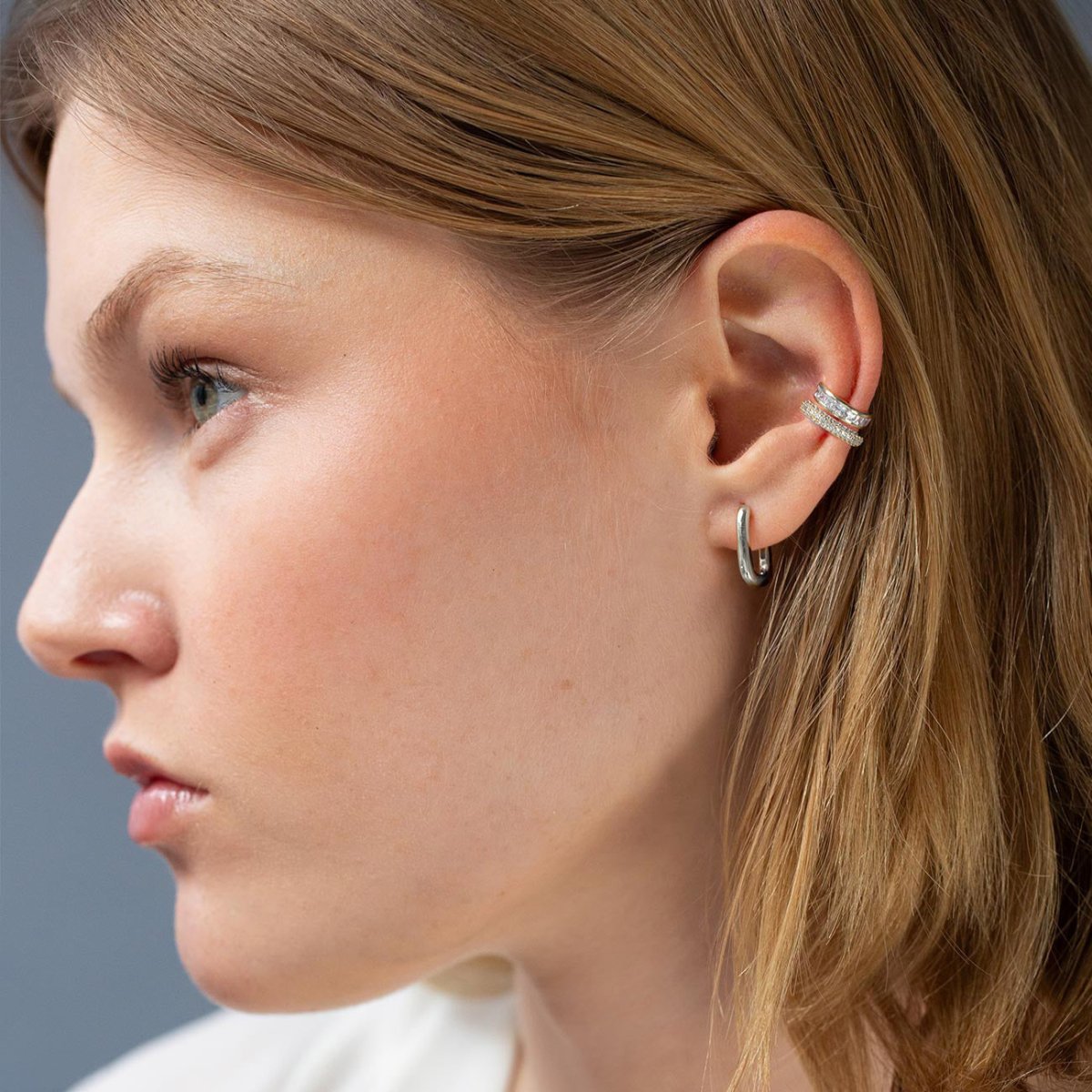 Silver hoop and pavé clear-stone ear cuffs stacked on a model's ear