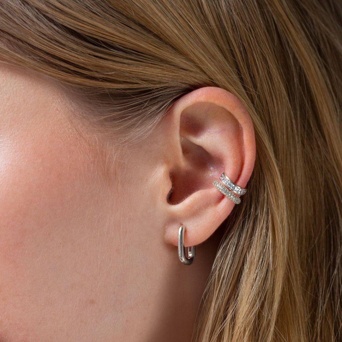 Sterling silver clear-stone ear cuff shown close-up on a model's upper ear