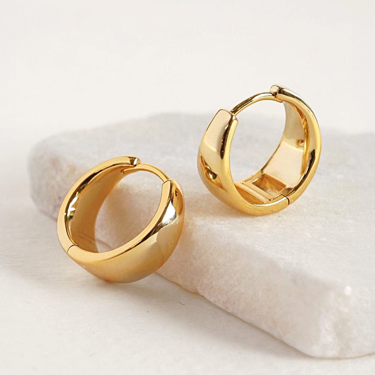 Gold vermeil bold teardrop small huggie hoops, shown in two sizes on white marble