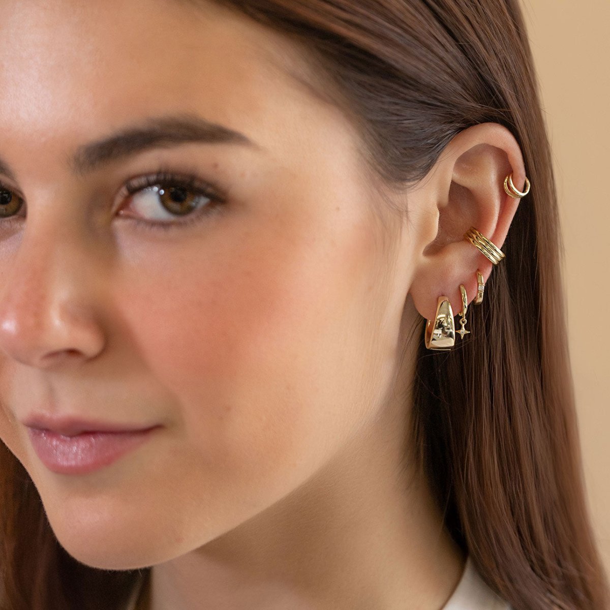 Gold vermeil bold teardrop small huggie hoop shown on a model's lobe in an ear stack