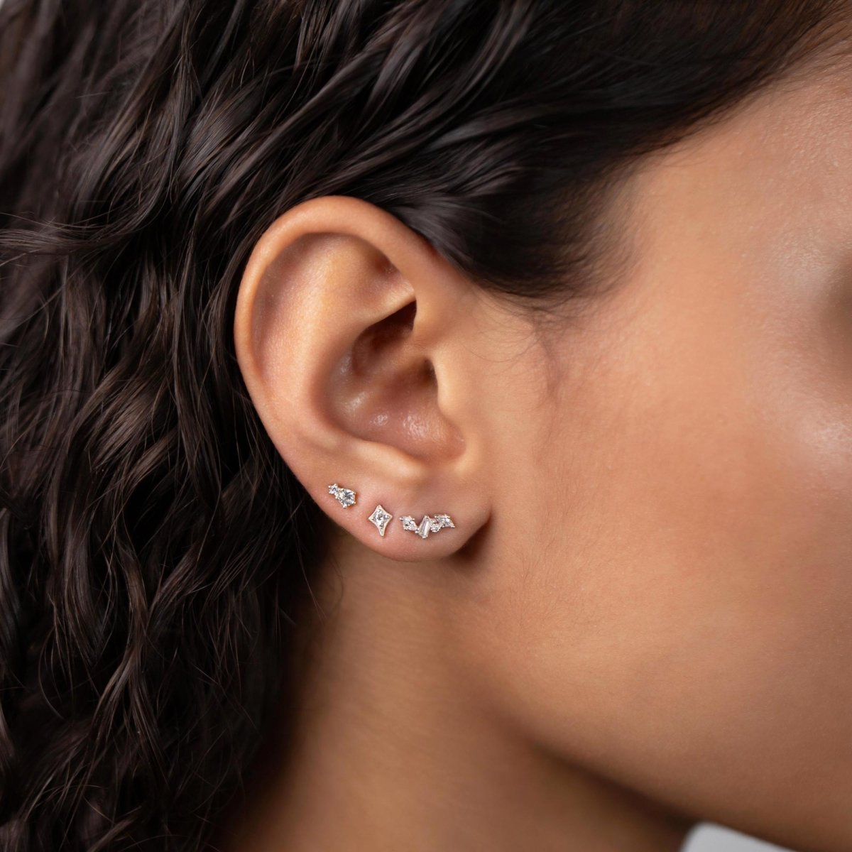 Sterling silver flare stud with clear zirconia, shown in an ear stack on a model's lobe